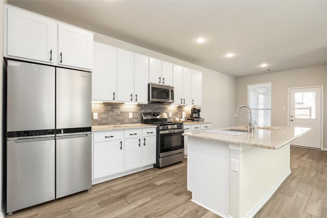 kitchen featuring a kitchen island with sink, sink, white cabinets, and appliances with stainless steel finishes