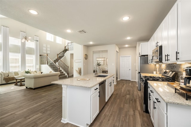 kitchen with sink, stainless steel appliances, an island with sink, and white cabinets