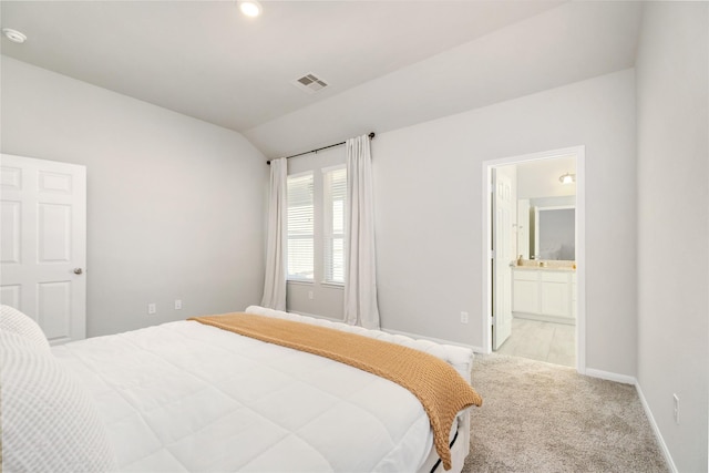 carpeted bedroom featuring vaulted ceiling and ensuite bathroom