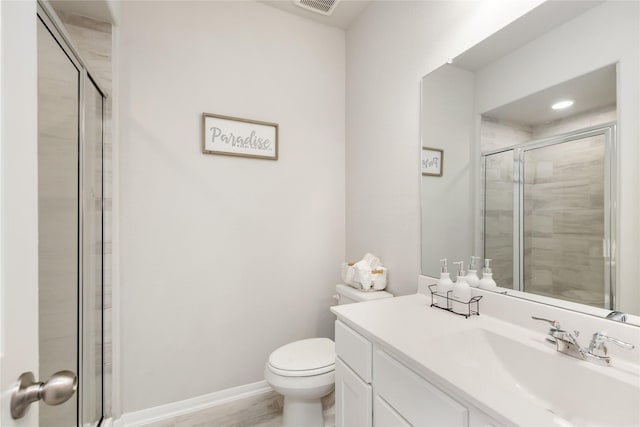 bathroom featuring vanity, a shower with shower door, and toilet