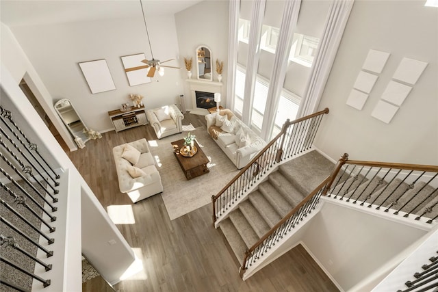 living room featuring hardwood / wood-style floors, ceiling fan, and a high ceiling