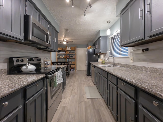 kitchen featuring sink, decorative light fixtures, gray cabinets, and appliances with stainless steel finishes