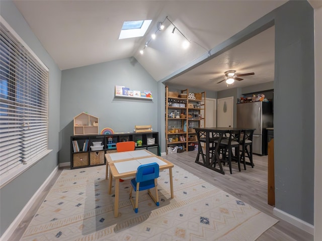 game room with hardwood / wood-style floors, vaulted ceiling with skylight, track lighting, and ceiling fan