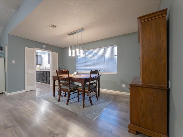 dining space with sink, a textured ceiling, and light wood-type flooring