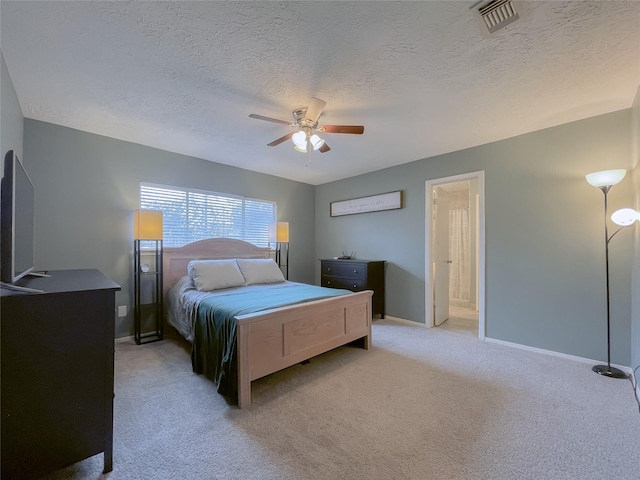 carpeted bedroom with a textured ceiling, ceiling fan, and ensuite bath