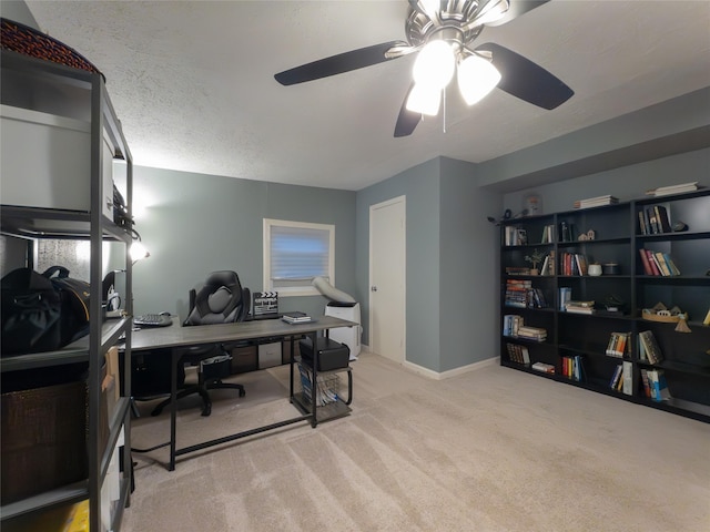 home office featuring light carpet, ceiling fan, and a textured ceiling