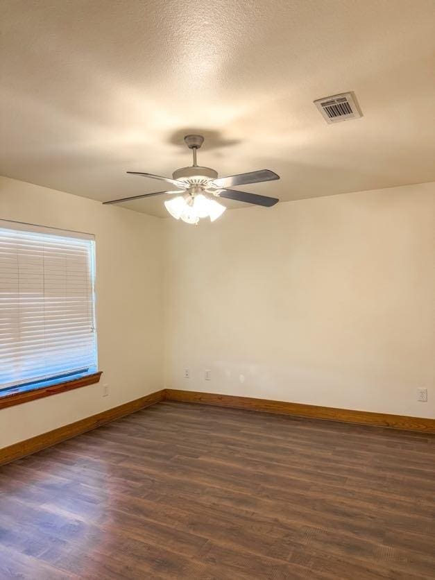 empty room featuring dark wood-type flooring and ceiling fan