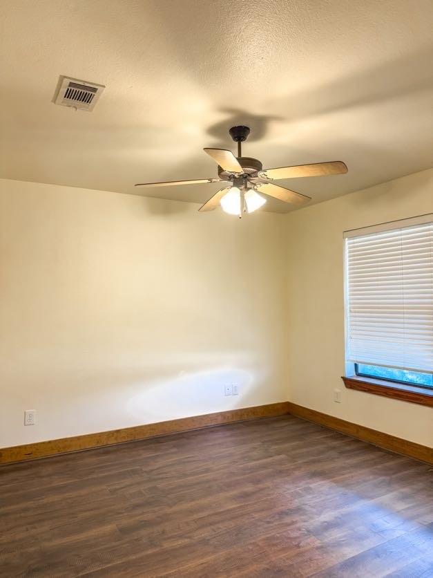 empty room featuring ceiling fan, a textured ceiling, and dark hardwood / wood-style flooring