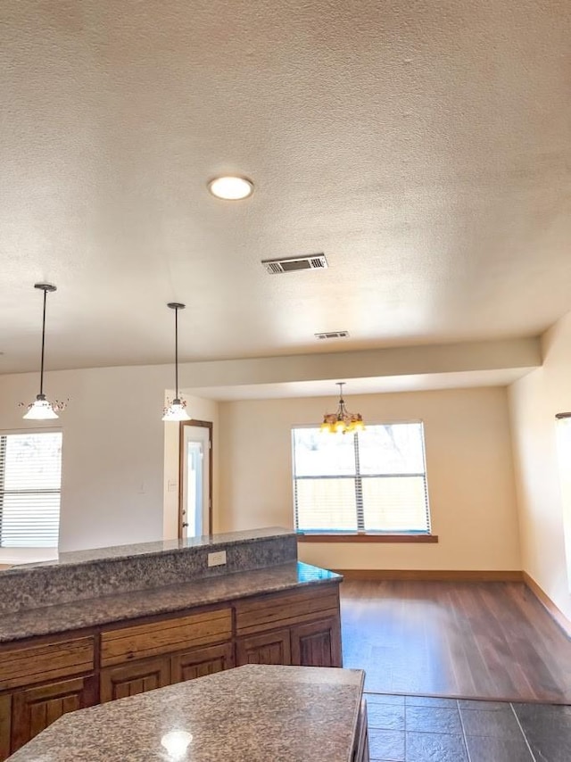 kitchen with decorative light fixtures, dark wood-type flooring, and a textured ceiling