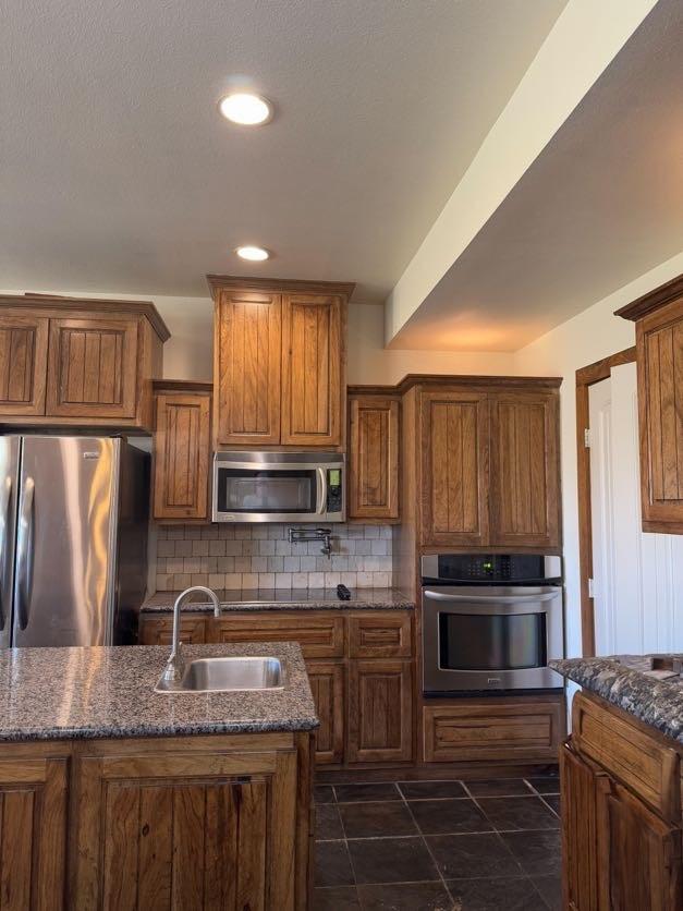 kitchen featuring dark stone countertops, sink, tasteful backsplash, and stainless steel appliances