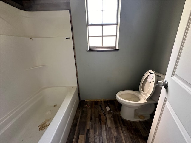 bathroom featuring wood-type flooring, a bath, and toilet