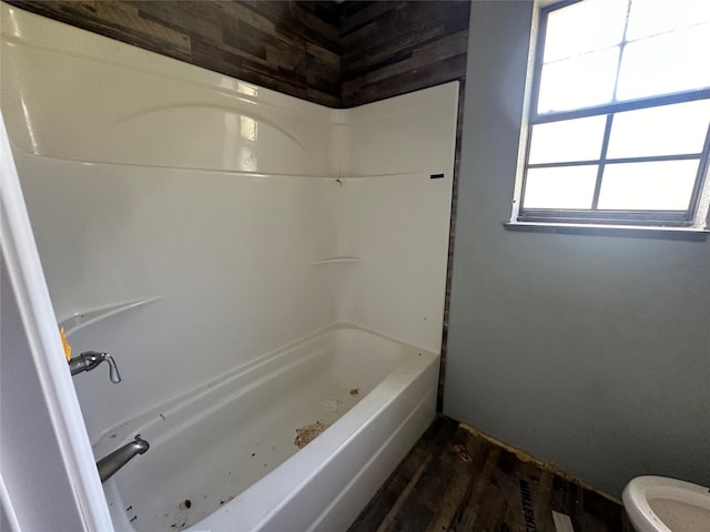 bathroom featuring wood-type flooring, toilet, and washtub / shower combination