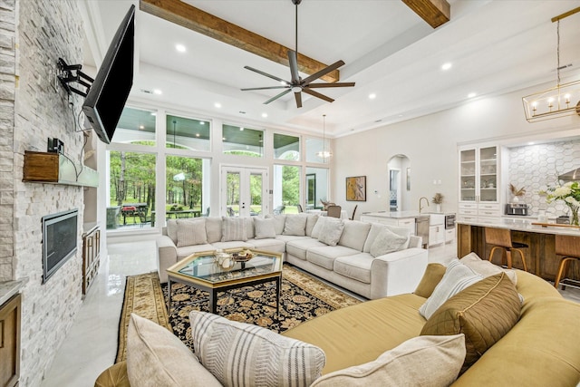 living room featuring beam ceiling, a fireplace, french doors, and a high ceiling