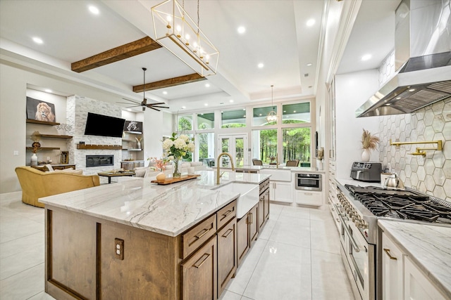 kitchen with a large island, sink, double oven range, light stone counters, and extractor fan