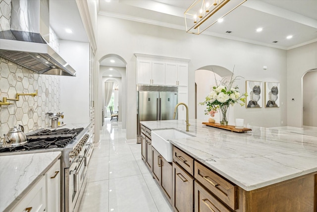 kitchen featuring sink, white cabinetry, light stone counters, double oven range, and island exhaust hood