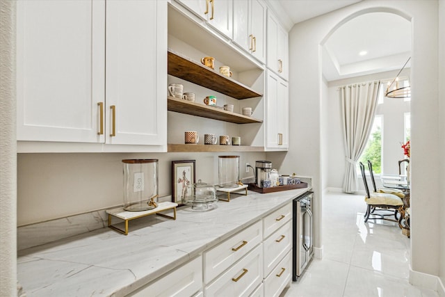 bar featuring white cabinetry, beverage cooler, light stone counters, and light tile patterned floors