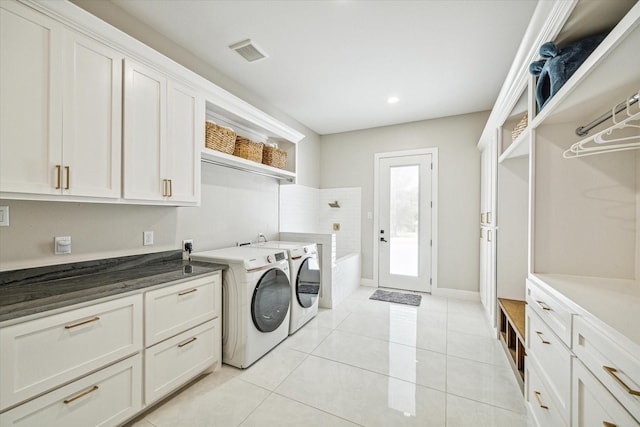 clothes washing area with light tile patterned floors, cabinets, and washing machine and clothes dryer