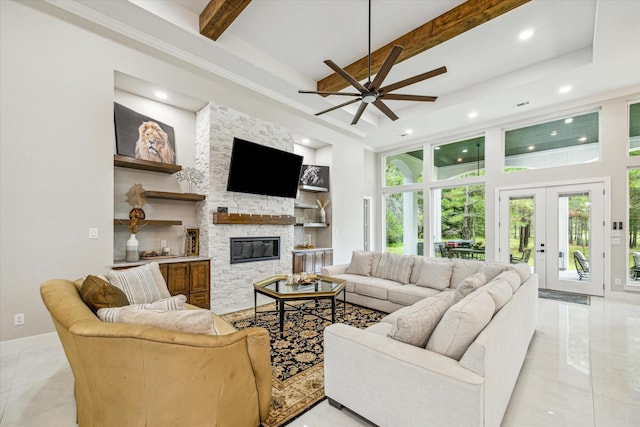 tiled living room featuring beamed ceiling, a towering ceiling, a stone fireplace, and french doors