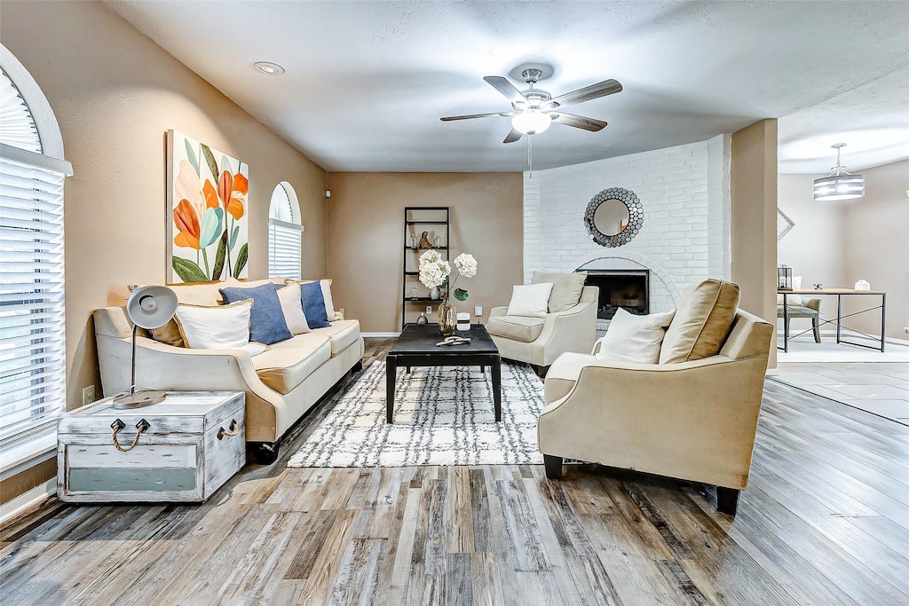 living room featuring ceiling fan, a fireplace, and hardwood / wood-style floors