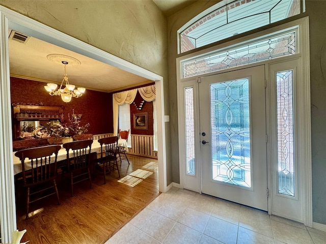 foyer with visible vents, a notable chandelier, light wood finished floors, and baseboards