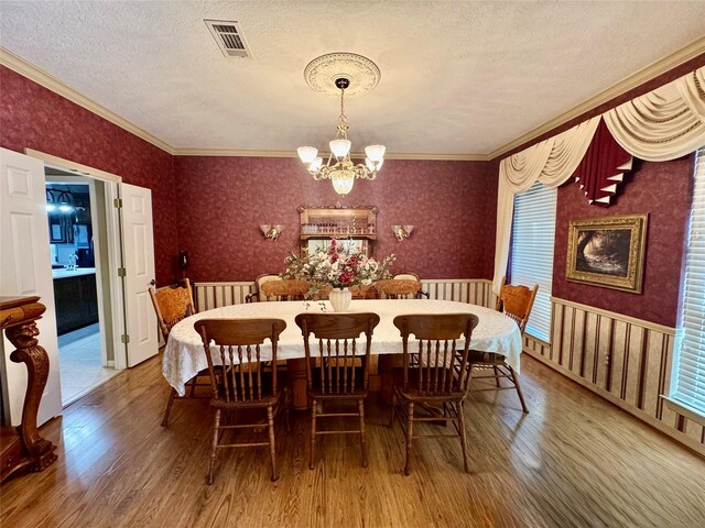 dining space featuring hardwood / wood-style flooring, crown molding, a notable chandelier, and a textured ceiling