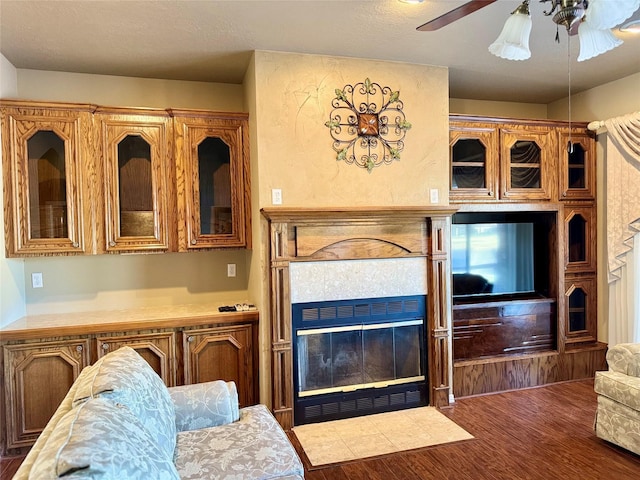 kitchen with light countertops, brown cabinetry, a tiled fireplace, and glass insert cabinets