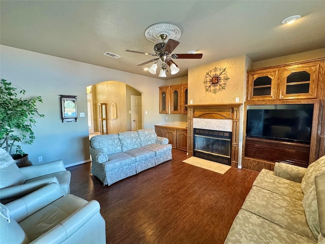 living room with ceiling fan, dark hardwood / wood-style floors, and a tiled fireplace