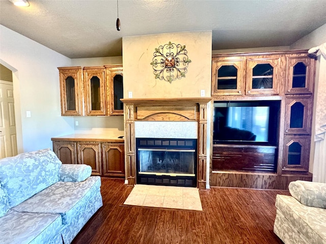 living room featuring dark hardwood / wood-style flooring, a tile fireplace, and a textured ceiling