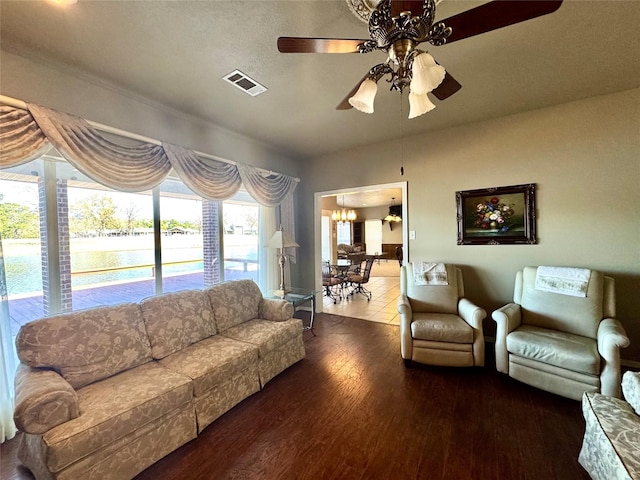 living area with a ceiling fan, visible vents, a water view, and wood finished floors