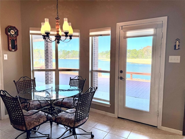 dining space with light tile patterned floors, a water view, baseboards, and a notable chandelier