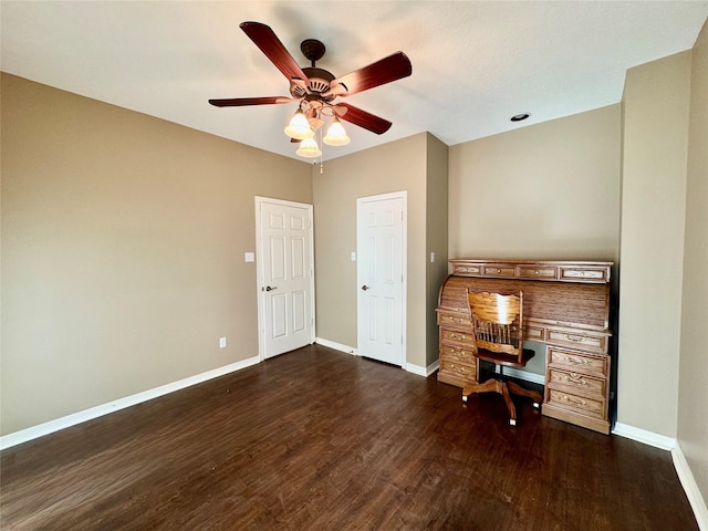 unfurnished office featuring dark wood-type flooring, ceiling fan, and baseboards