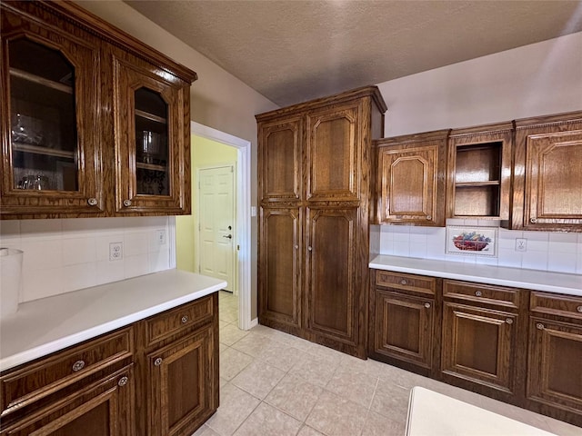 kitchen featuring glass insert cabinets, light countertops, and dark brown cabinetry