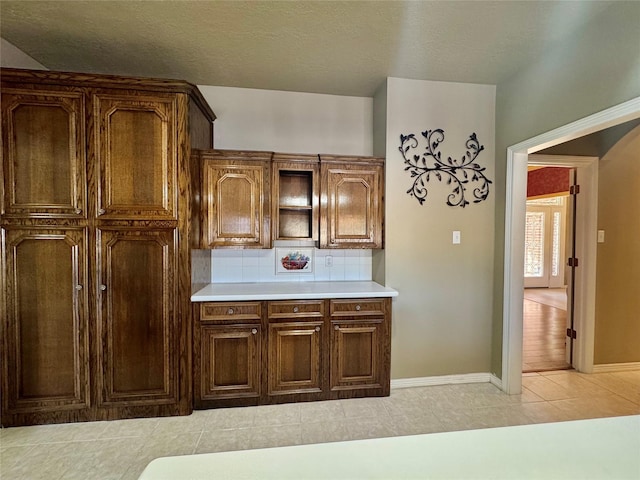 kitchen featuring light tile patterned floors, light countertops, tasteful backsplash, and baseboards