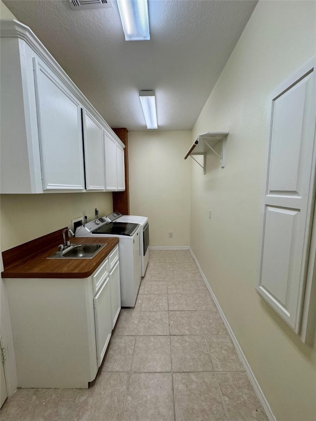 laundry area with sink, cabinets, a textured ceiling, washing machine and clothes dryer, and light tile patterned flooring