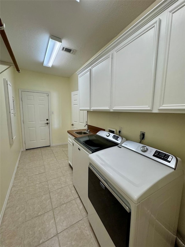 clothes washing area featuring light tile patterned floors, cabinet space, visible vents, independent washer and dryer, and baseboards