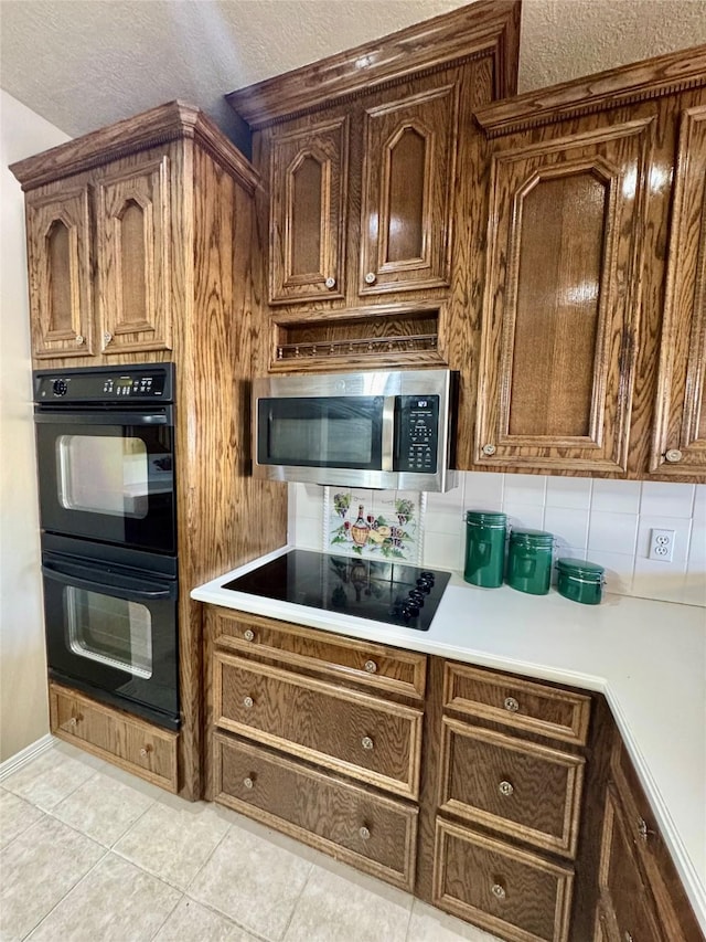 kitchen with black appliances, light countertops, decorative backsplash, and light tile patterned flooring