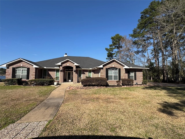 view of front of house with a front yard, brick siding, and a chimney