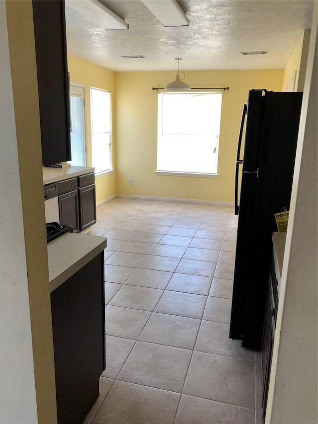 kitchen featuring light tile patterned flooring, black fridge, and a textured ceiling