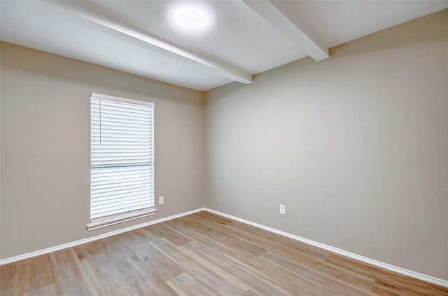 unfurnished room with light hardwood / wood-style floors and beamed ceiling