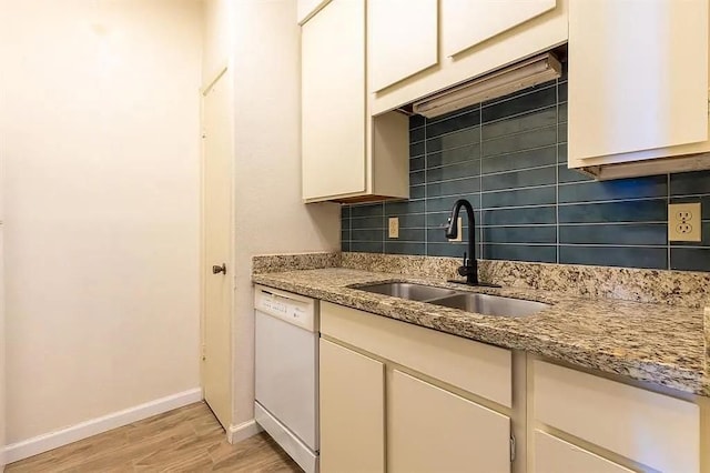 kitchen with sink, dishwasher, light stone countertops, decorative backsplash, and light wood-type flooring