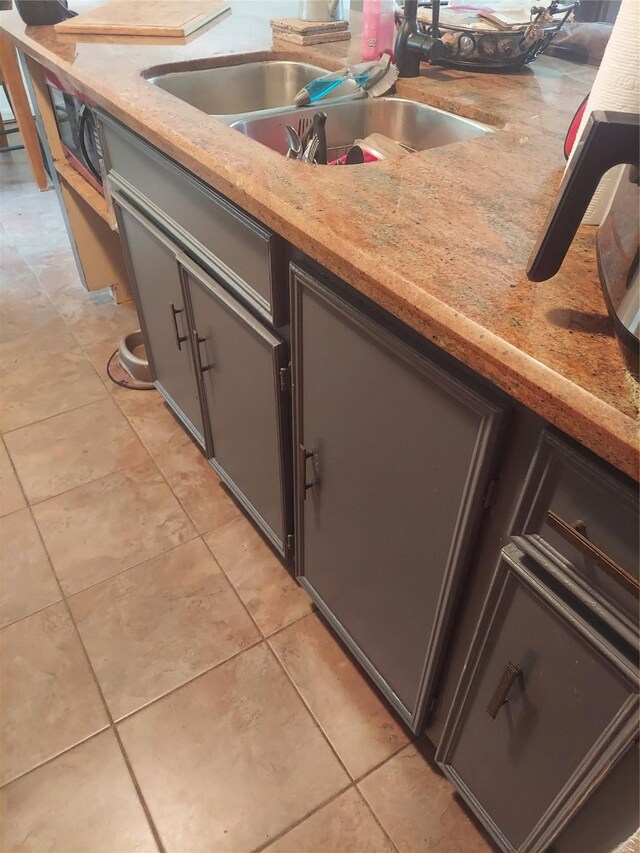 kitchen featuring light stone countertops, sink, and light tile patterned floors