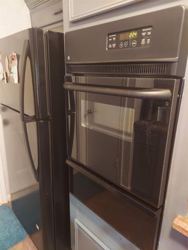 room details featuring white cabinetry and black refrigerator