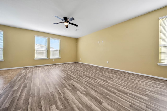 unfurnished room featuring baseboards, ceiling fan, light wood finished floors, and a healthy amount of sunlight