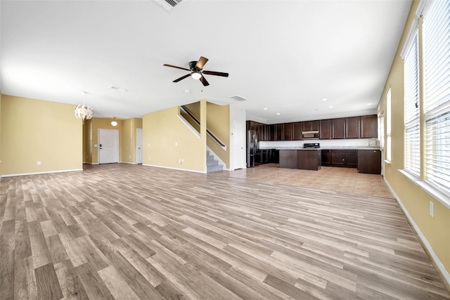 unfurnished living room featuring baseboards, visible vents, light wood finished floors, and stairs