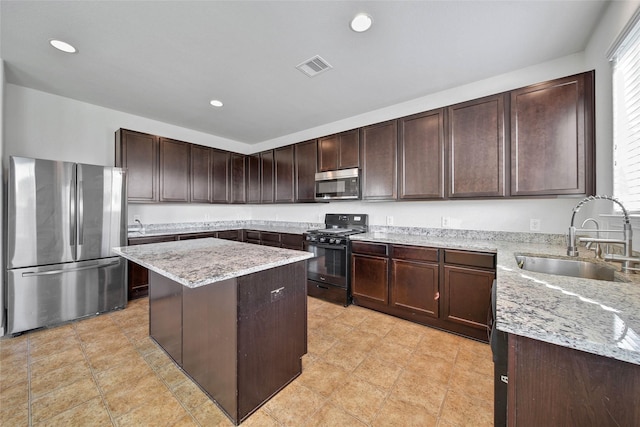 kitchen featuring sink, dark brown cabinets, stainless steel appliances, a center island, and light stone counters