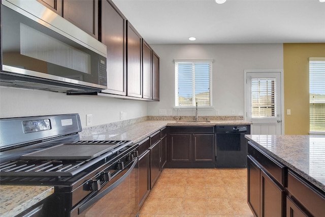 kitchen with light stone counters, light tile patterned floors, a sink, dark brown cabinets, and black appliances