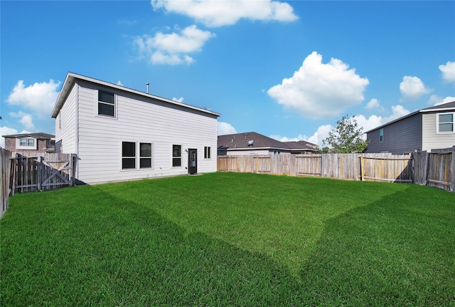 back of house featuring a fenced backyard and a lawn