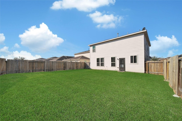 rear view of house featuring a lawn and a fenced backyard