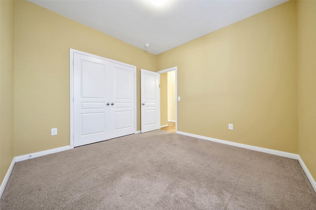 unfurnished bedroom with a closet, carpet flooring, and baseboards