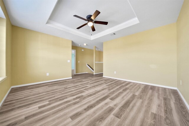 spare room featuring light hardwood / wood-style flooring, a raised ceiling, and ceiling fan